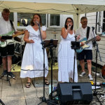 two women singing with a band in a garden