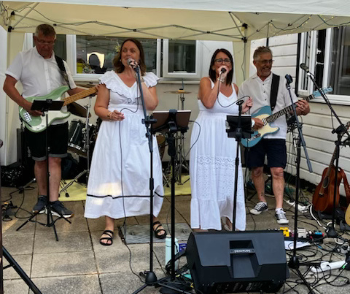 two women singing with a band in a garden