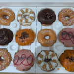 a box of doughnuts, one with the name blakeney house written in icing